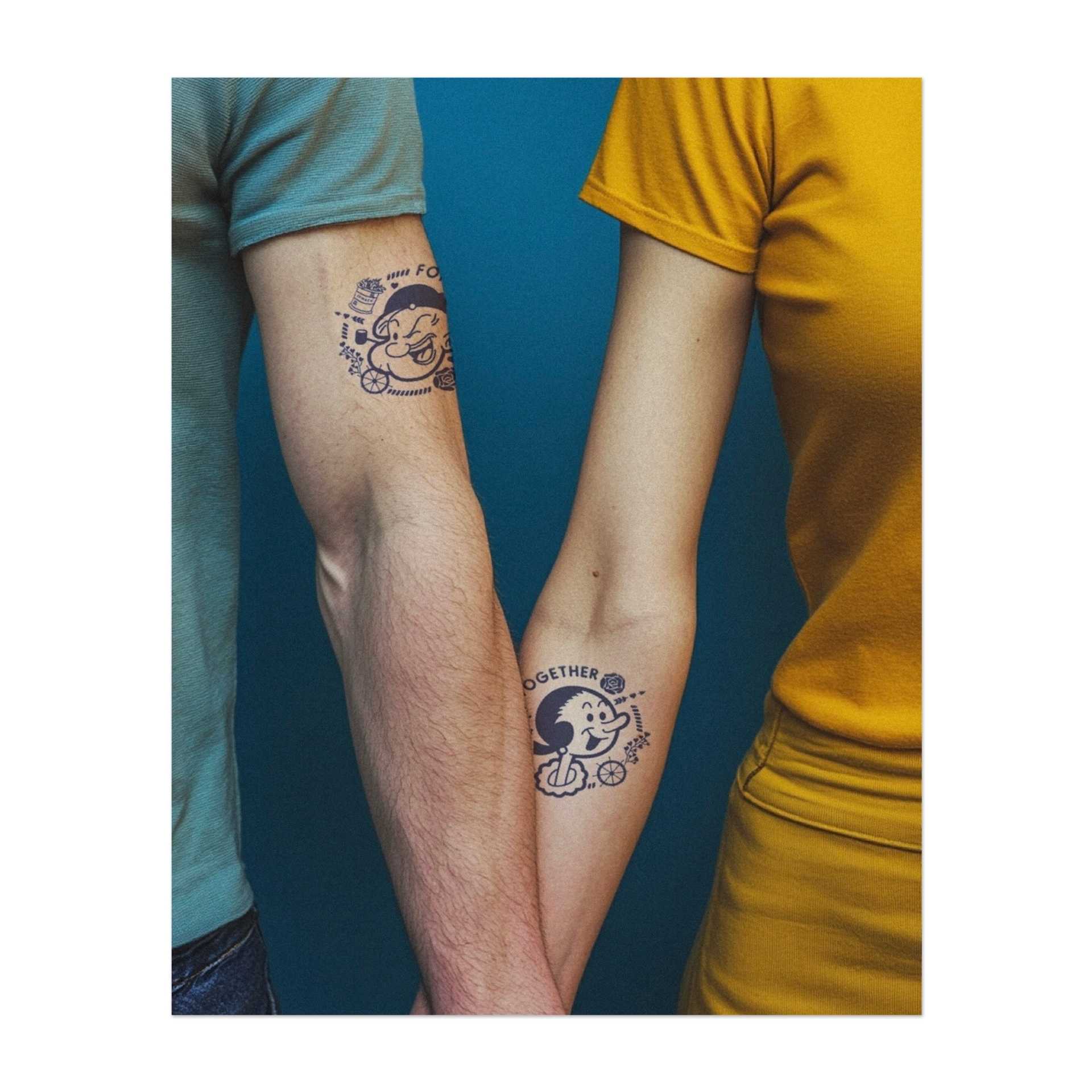Ein verspieltes Tattoo-Set mit Popeye und Olive Oyl, begleitet von den Worten "Forever" und "Together". Umgeben von Ankern, Rosen und Herzen symbolisiert es Liebe und Loyalität im Stil alter Cartoons.