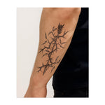 Une grande vigne avec des épines acérées et des branches torsadées, ornée de feuilles. Le tatouage représente la croissance à travers l'adversité, les épines symbolisant les défis et les feuilles montrant la résilience et la force.