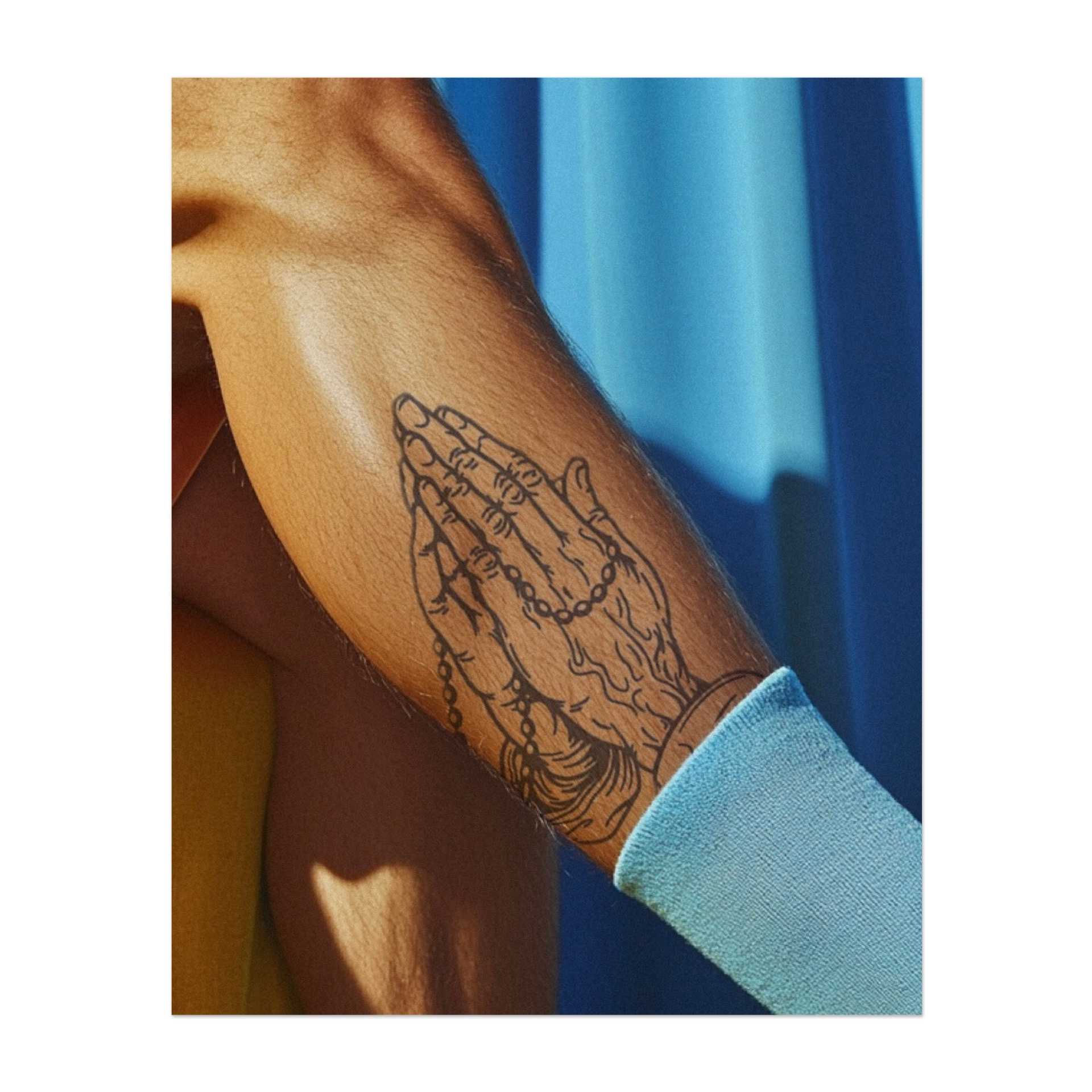 Ein detailliertes Tattoo von zwei Händen, die im Gebet zusammengelegt sind, mit einer Rosenkranzperle dazwischen. Dieses Design symbolisiert Glauben, Hoffnung und Hingabe. Eine wunderschöne Wahl für jemanden, der Spiritualität schätzt und ein friedliches, bedeutungsvolles Symbol sucht.