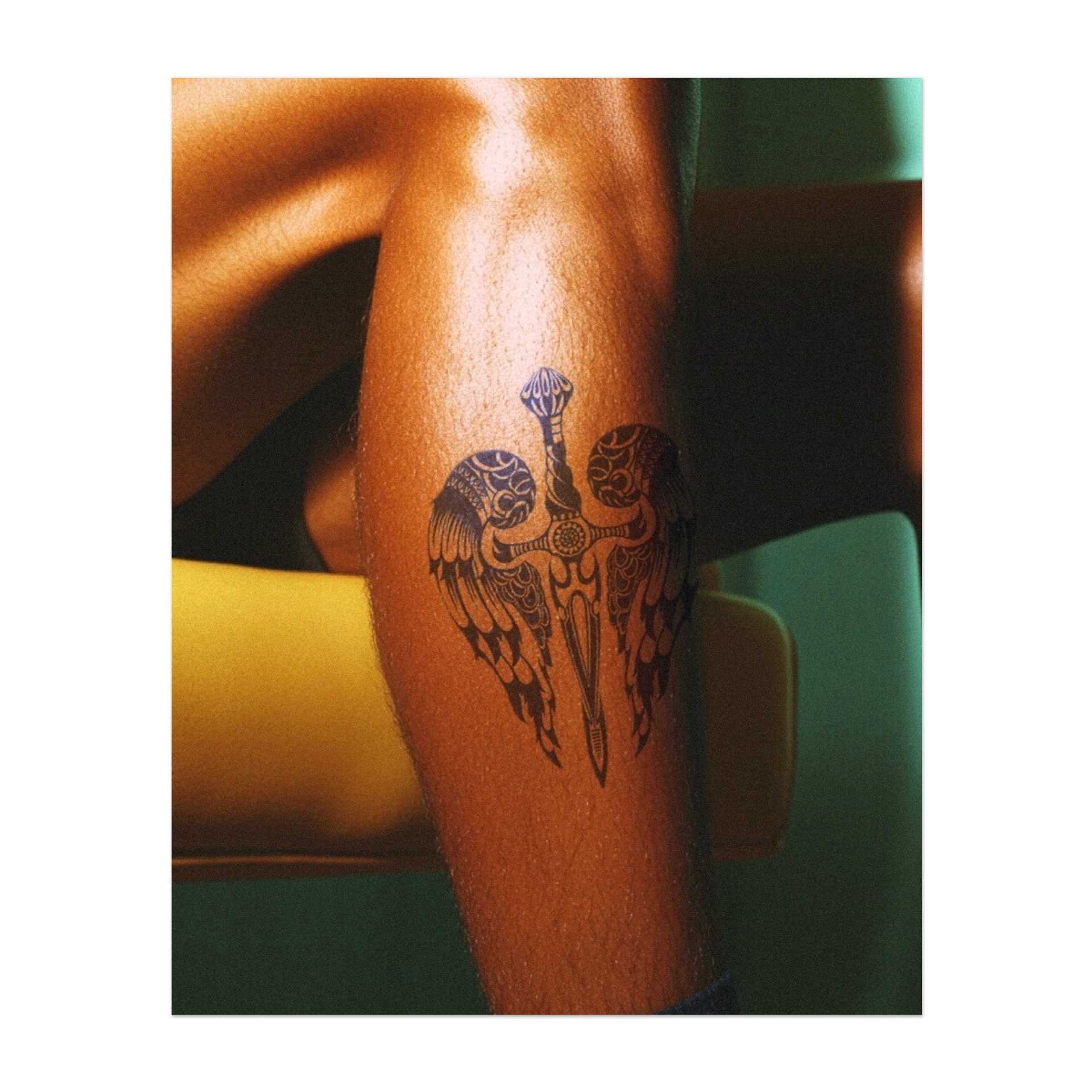 Ein detailliertes Schwert mit Flügeln, die von beiden Seiten ausgehen, symbolisiert ein Gleichgewicht zwischen Stärke und Anmut. Dieses Tattoo repräsentiert Schutz, Tapferkeit und göttliche Macht und ist ideal für jemanden, der sowohl Mut als auch inneren Frieden schätzt.