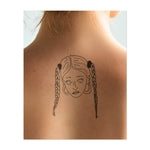 Un tatouage minimaliste d'une femme avec deux tresses et de grandes boucles d'oreilles créoles. Son expression calme et ses lignes délicates capturent une humeur cool et insouciante. Le design est simple et élégant, dessiné avec des lignes épurées.
