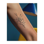 Eine wunderschöne Rose, durchbohrt von einem scharfen Pfeil, mit Blütenblättern und Blättern, die sich darum winden. Dieses Tattoo ist in einem zarten Stil gehalten und gibt ihm eine weiche, fast vintage Ausstrahlung. Es ist eine Mischung aus Eleganz und Stärke, perfekt für diejenigen, die Natur und Mut lieben.
