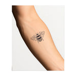 Un dessin de tatouage minimaliste d'une abeille dans un style de ligne simple. L'abeille est représentée en vol, avec des rayures audacieuses et des ailes détaillées, ce qui la fait ressortir.